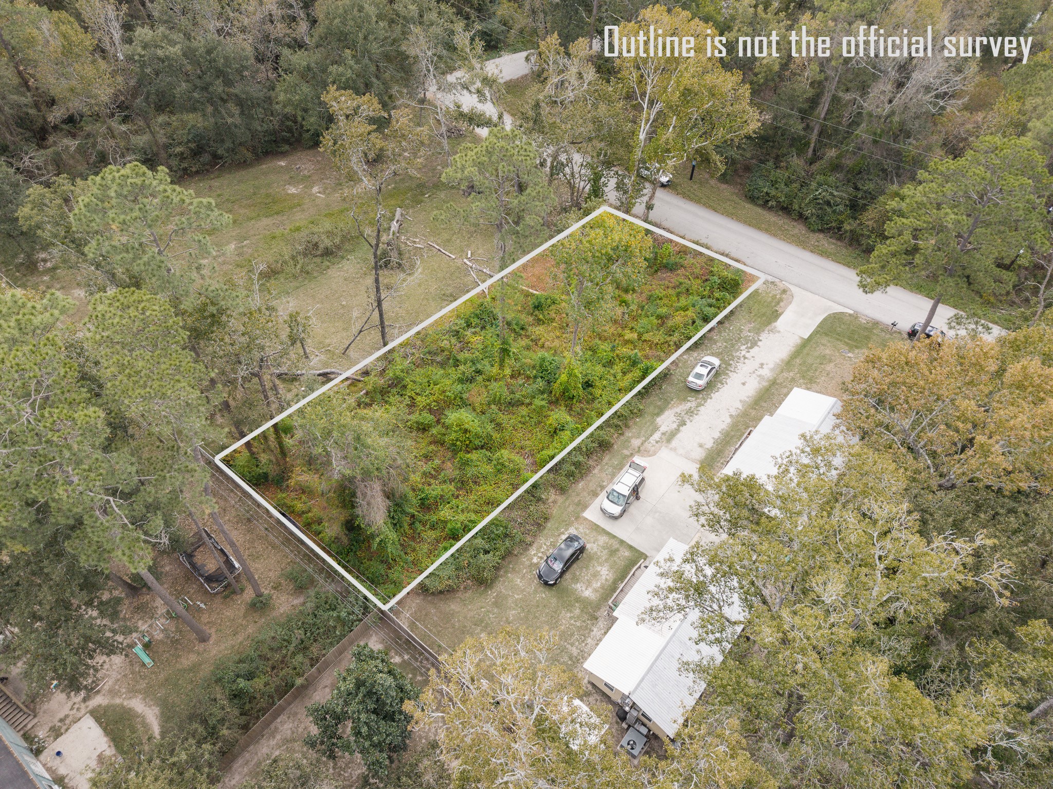 22030 Rustic Bridge Lane Houston, TX 77339 - Photo 5 of 7 This aerial photo shows a rectangular plot of land outlined in white, surrounded by trees. The lot is located near a road, with some vehicles parked nearby. The area appears to be wooded, offering a natural setting.