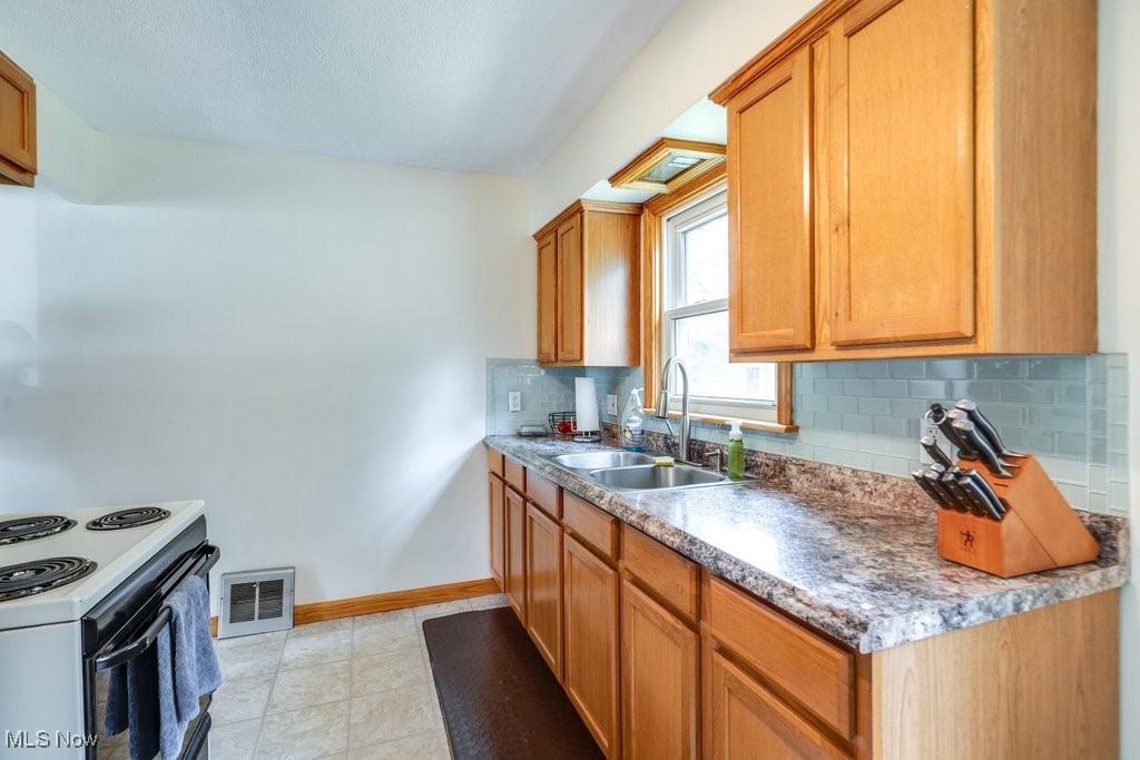 11339 Ridge Road North Royalton, OH 44133 - Photo 5 of 22 Kitchen featuring tasteful backsplash, white range with electric cooktop, and brown cabinetry