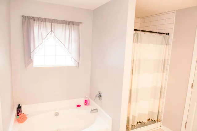 a bathroom with a bathtub a shower and a window