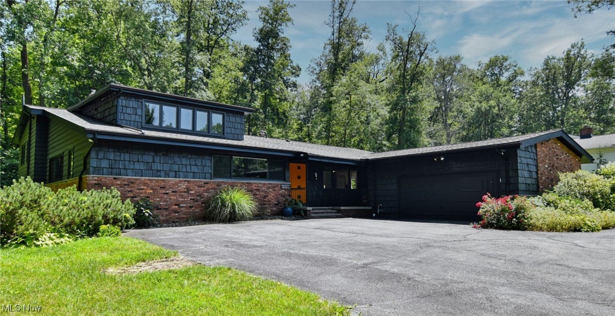 Mid-century inspired home featuring a garage, asphalt driveway, and brick siding