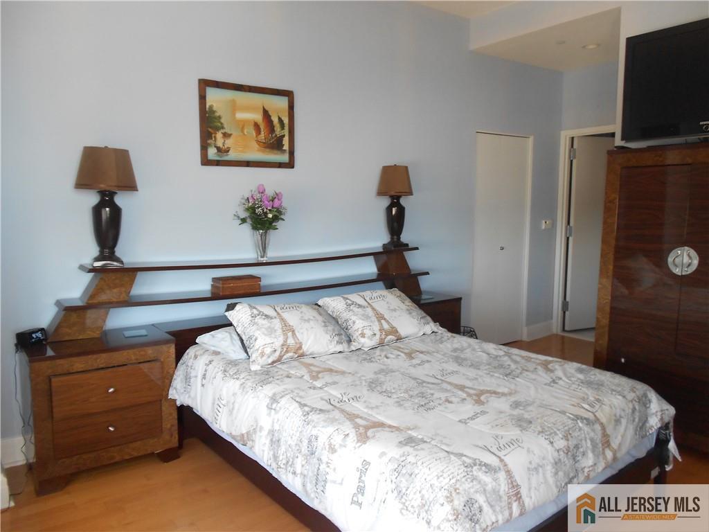 1 Spring Street, Unit 2305 New Brunswick, NJ 08901 - Photo 17 of 29 a bedroom with a bed and a flat tv screen on a dresser