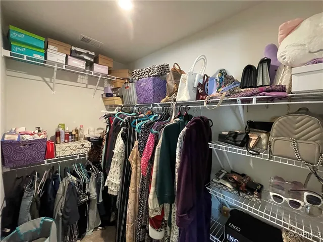 a view of walk in closet with clothes and shoes
