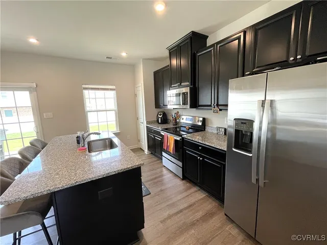 a kitchen with stainless steel appliances granite countertop a refrigerator a stove a sink a dining table and chairs