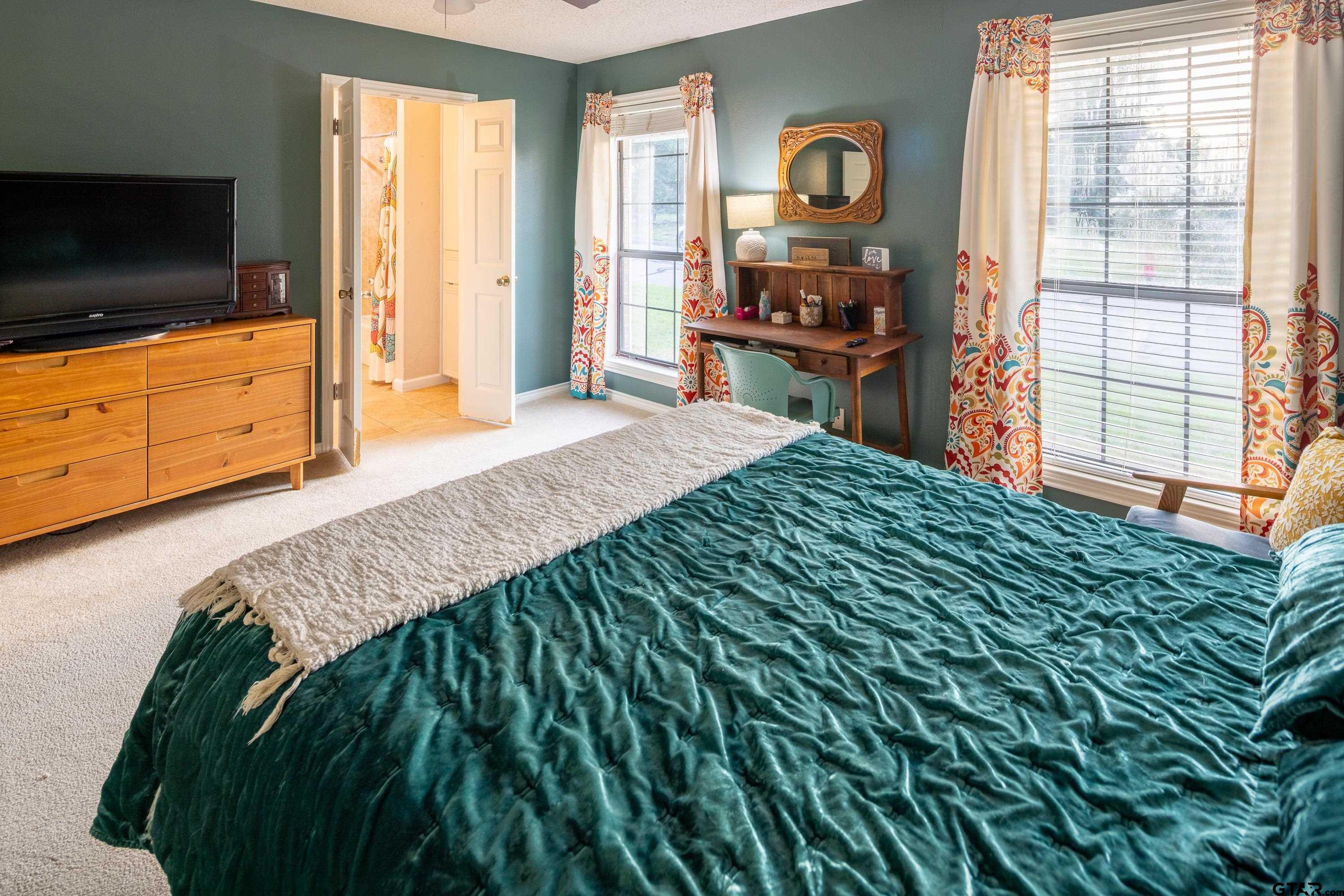 2900 West Azalea Drive Tyler, TX 75701 - Photo 17 of 37 a bedroom with a bed and flat tv screen on the dresser