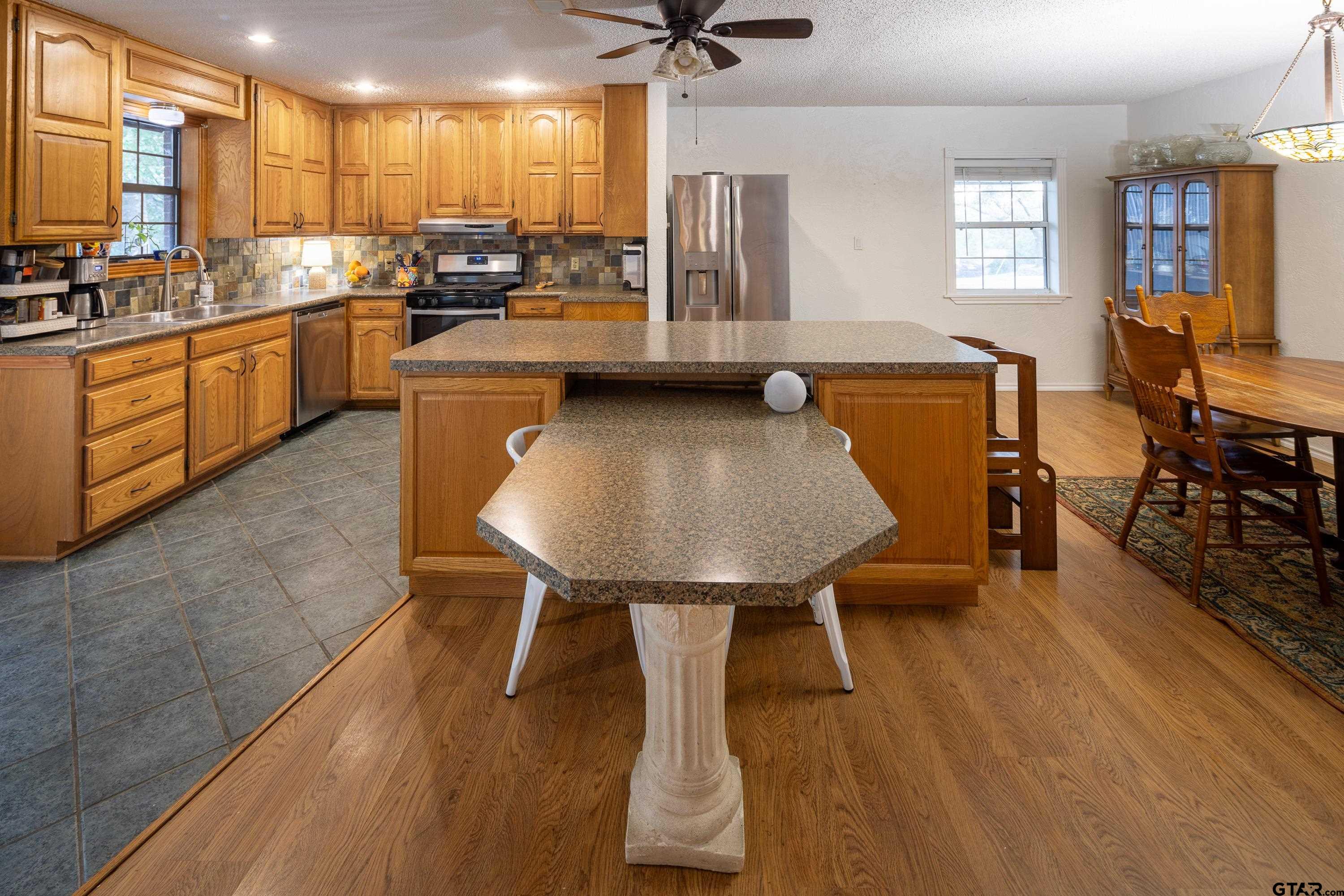 2900 West Azalea Drive Tyler, TX 75701 - Photo 9 of 37 a kitchen with stainless steel appliances kitchen island granite countertop a table chairs sink and cabinets