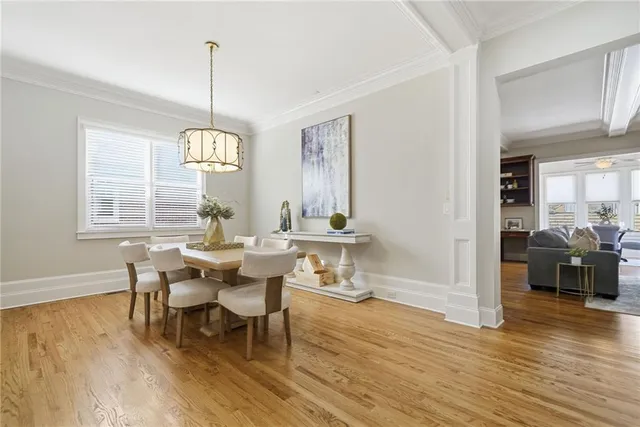 a dining room with wooden floor a chandelier a wooden table and chairs