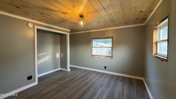 an empty room with wooden floor chandelier fan and windows