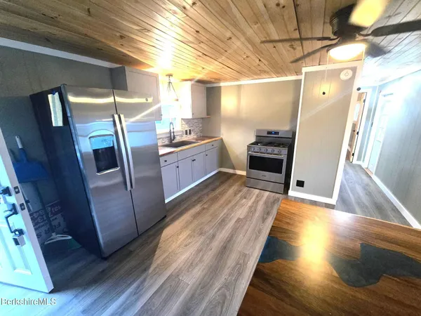 a kitchen with granite countertop a refrigerator and wooden floor