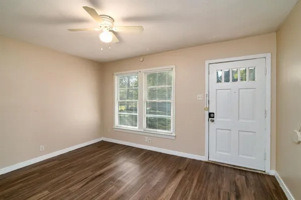 an empty room with wooden floor chandelier fan and windows