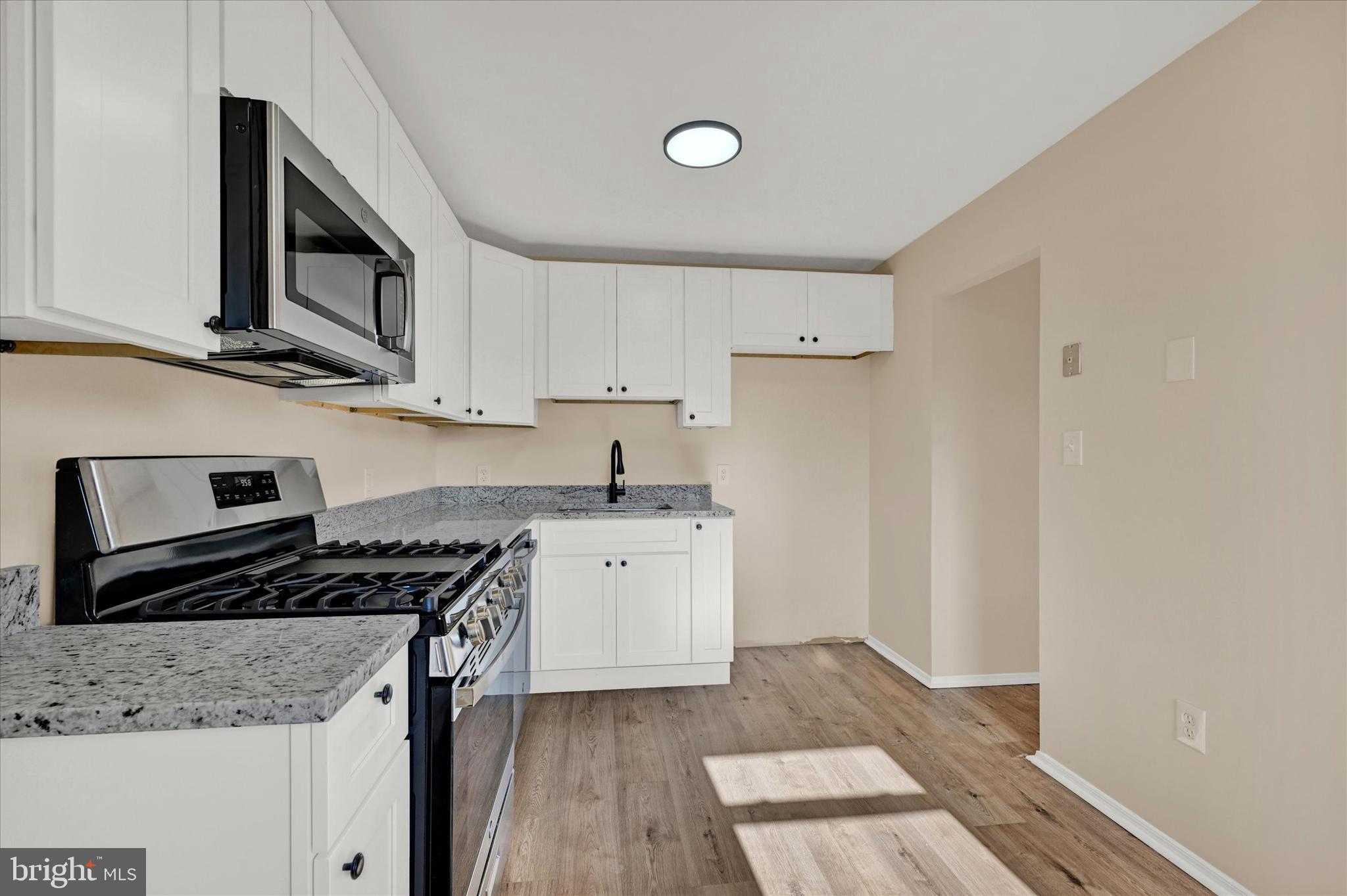 8577 Main Avenue Pasadena, MD 21122 - Photo 7 of 19 a kitchen with granite countertop a sink and a stove top oven