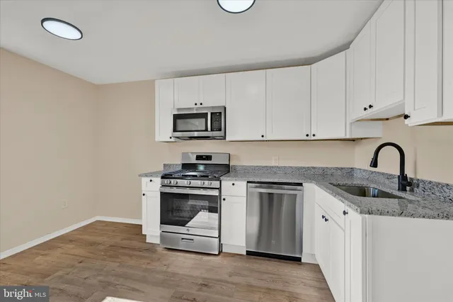 a kitchen with granite countertop a stove top oven a sink and dishwasher