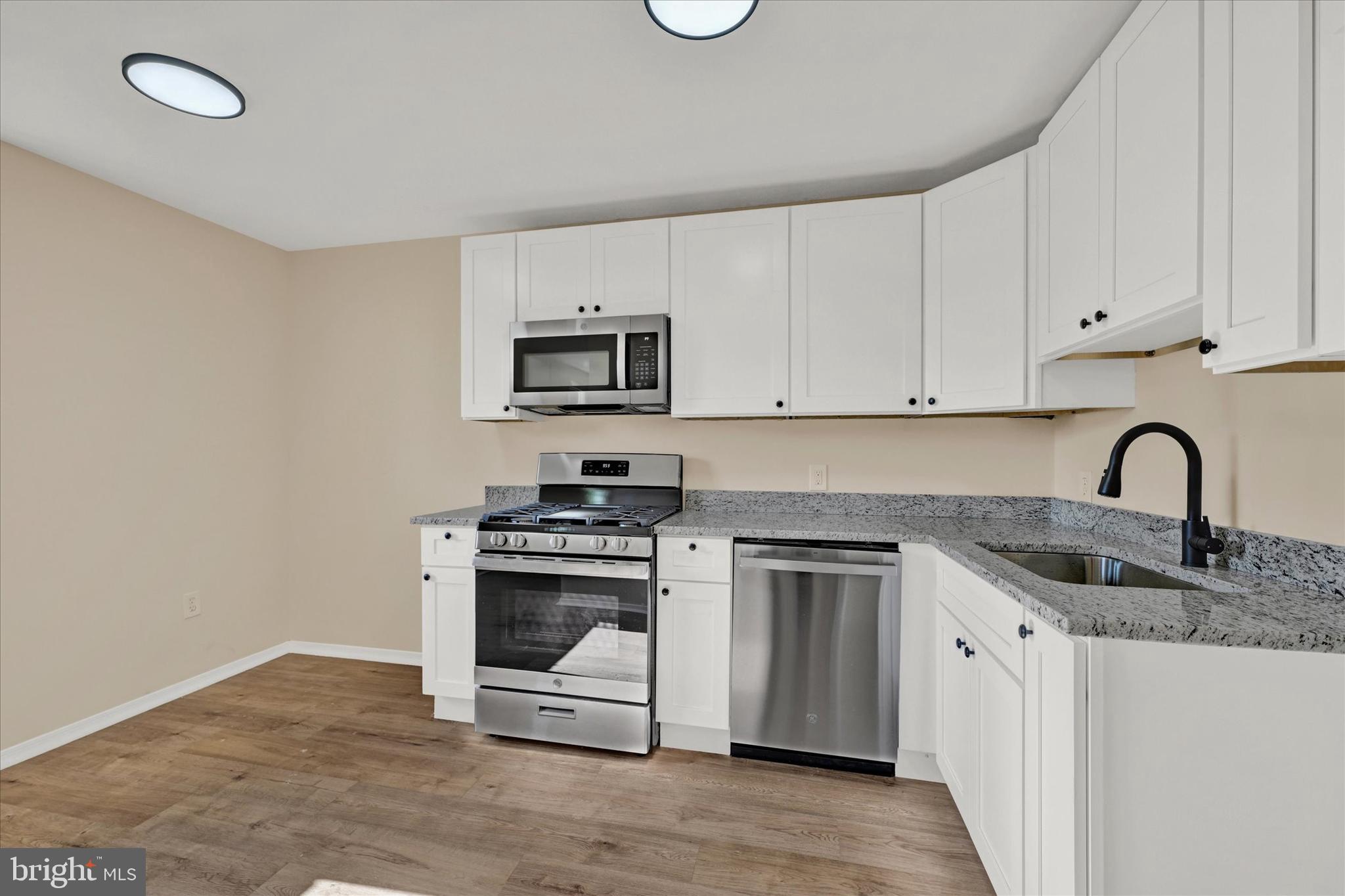 8577 Main Avenue Pasadena, MD 21122 - Photo 8 of 19 a kitchen with granite countertop a stove top oven a sink and dishwasher