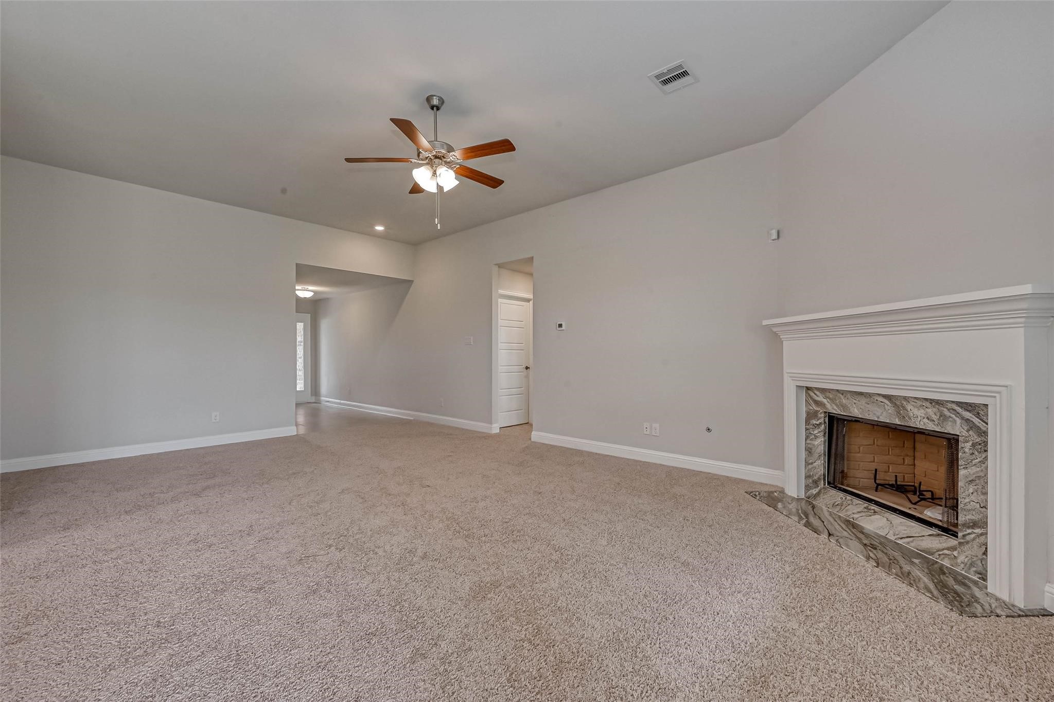 10238 Whitney Reach Drive Rosharon, TX 77583 - Photo 15 of 29 Spacious living room with plush carpet, a cozy fireplace with a sleek mantle, and a ceiling fan for comfort.