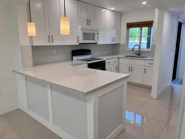a kitchen with white cabinets and window