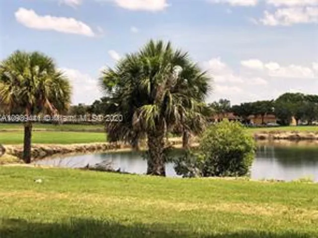 a front view of a house with a garden and lake view