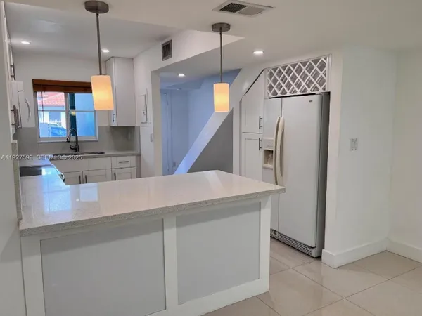 a kitchen with stainless steel appliances kitchen island granite countertop a refrigerator a oven and a sink with granite countertops