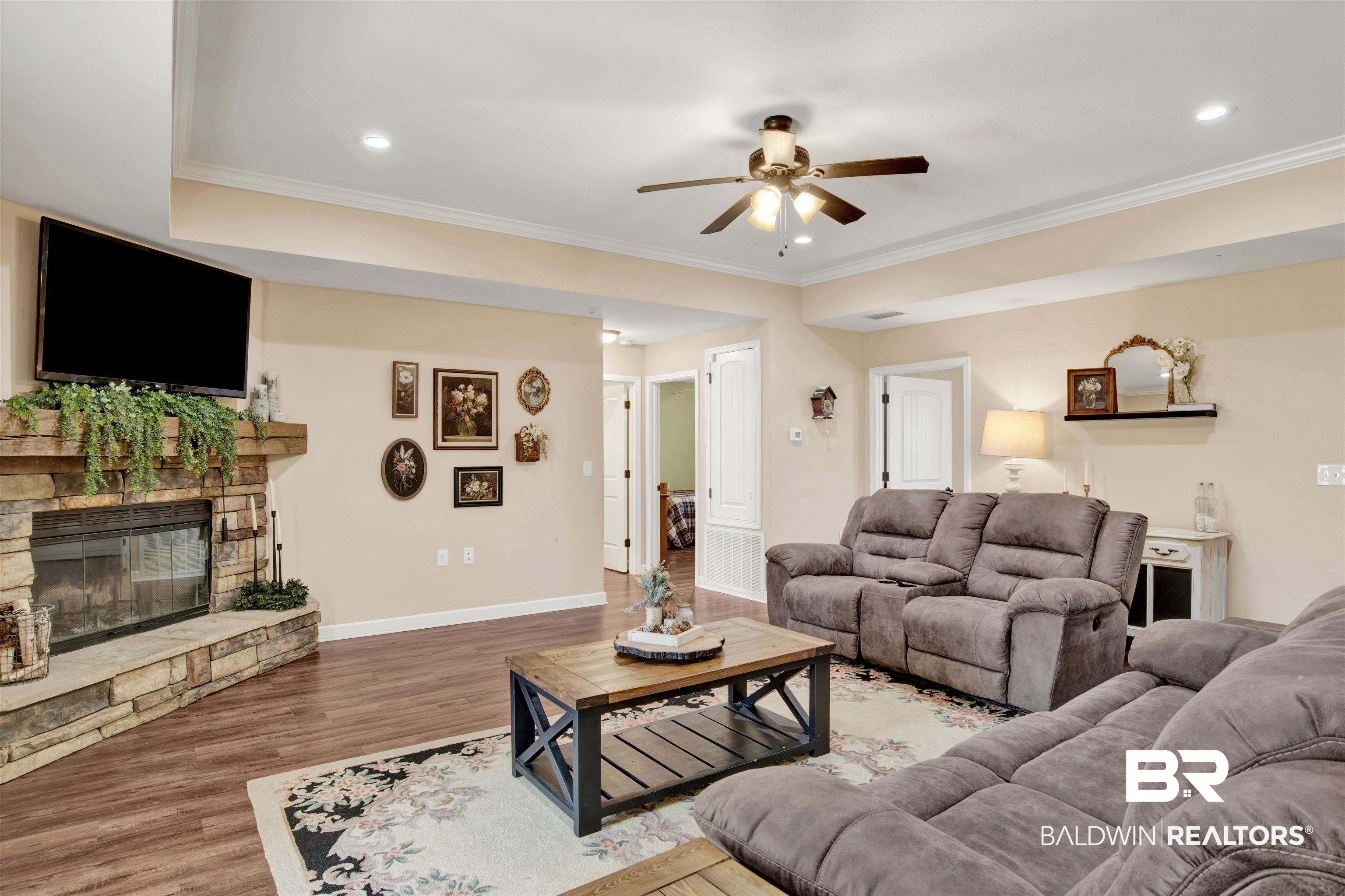 13676 Styx River Road Stapleton, AL 36578 - Photo 7 of 30 Living room featuring a stone fireplace, ceiling fan, crown molding, and wood-type flooring