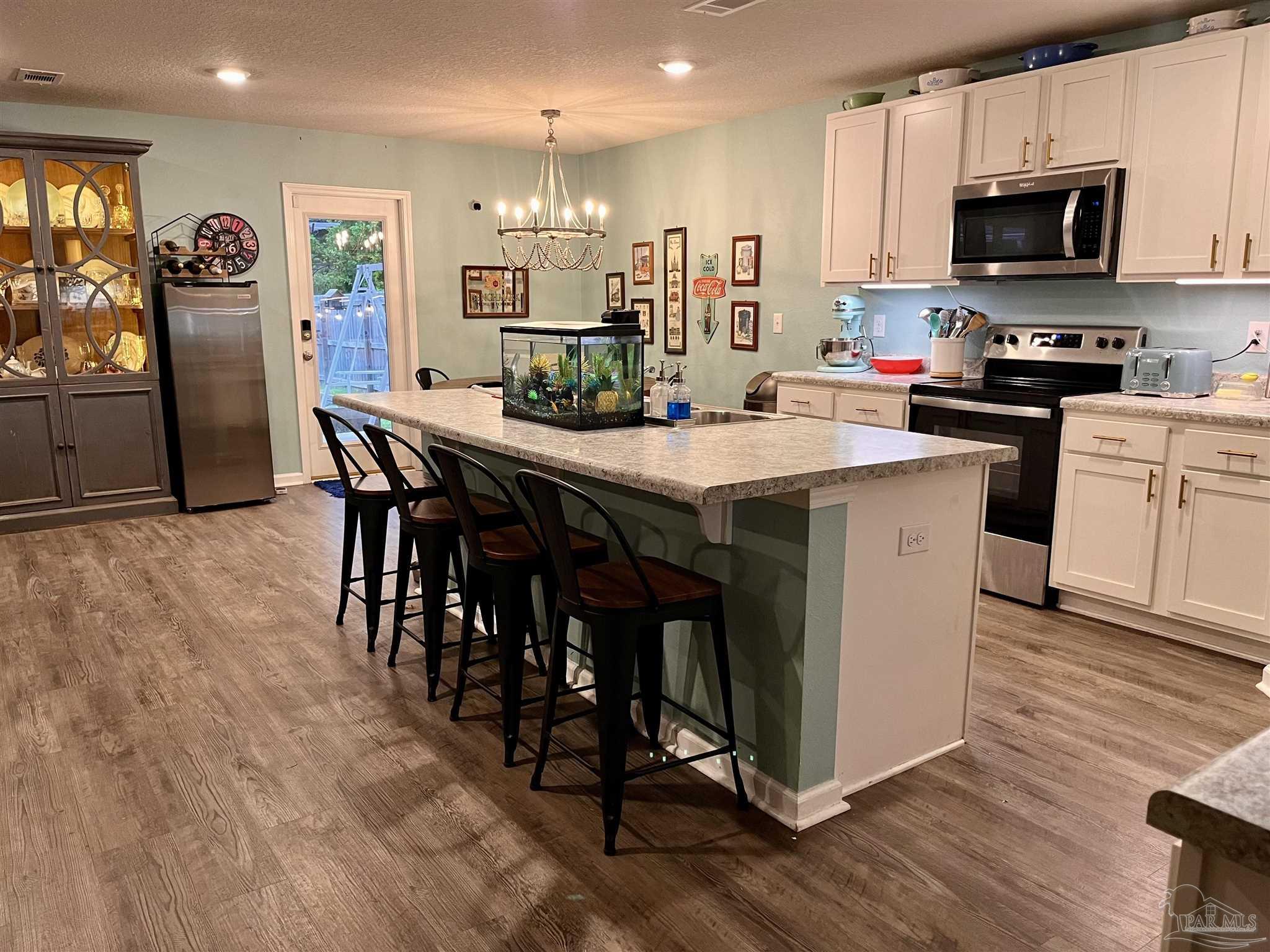 5375 Peach Drive Milton, FL 32571 - Photo 8 of 34 a kitchen with stainless steel appliances a microwave a stove a sink a refrigerator and white cabinets with wooden floor