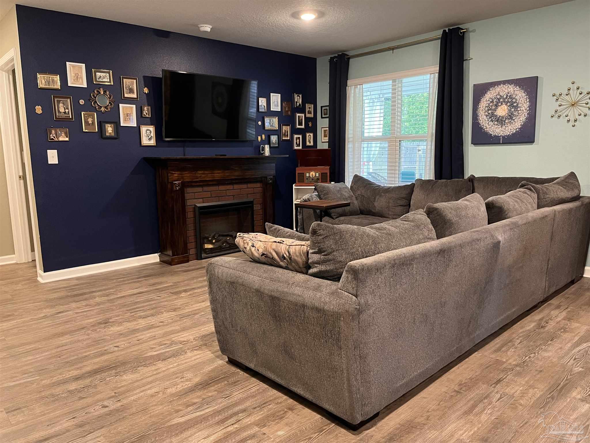 5375 Peach Drive Milton, FL 32571 - Photo 10 of 34 a living room with furniture a flat screen tv and a fireplace