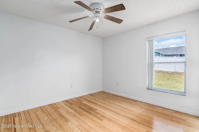 a view of empty room with wooden floor and ceiling fan