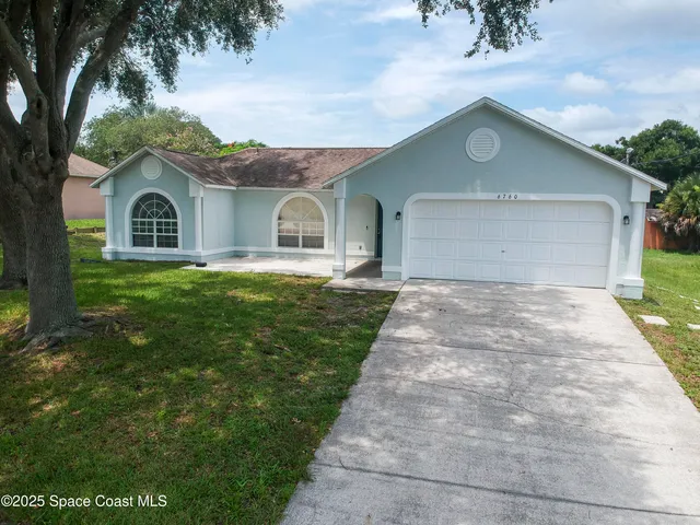 an aerial view of a house with a yard and a large tree