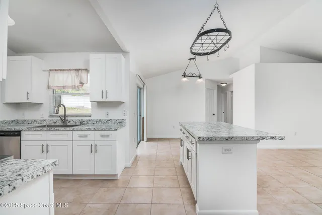 a kitchen with granite countertop a sink a stove top oven and cabinets