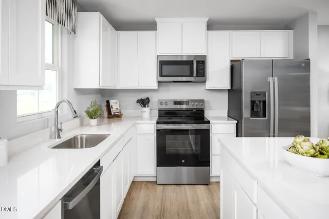 a kitchen with stainless steel appliances granite countertop a sink a stove a refrigerator and cabinets