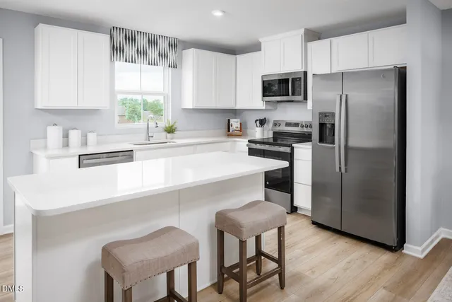 a kitchen with a sink white cabinets and stainless steel appliances