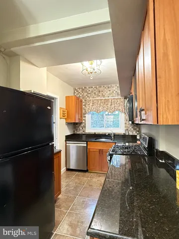 a kitchen with granite countertop a refrigerator a sink a stove top oven and a dishwasher