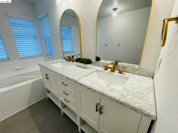 a spacious bathroom with a double vanity sink a large mirror and a bathtub