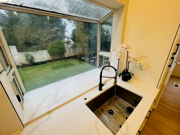 a kitchen with stainless steel appliances kitchen island granite countertop a sink a stove top oven a dining table and chairs with wooden floor