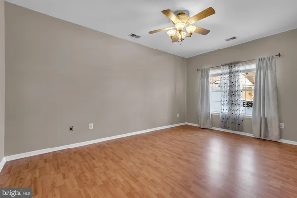 a view of an empty room with window and wooden floor