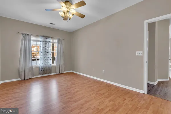 a view of an empty room with window and wooden floor