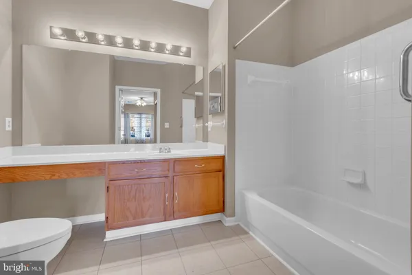 a bathroom with a granite countertop sink a toilet a mirror and bathtub