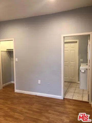 an empty room with wooden floor and a bathroom