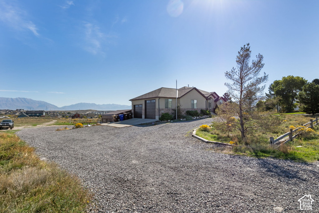 9044 North Cedar Pass Road Eagle Mountain, UT 84005 - Photo 62 of 63 Gravel driveway leading to a residence with a two-car garage and stone accents
