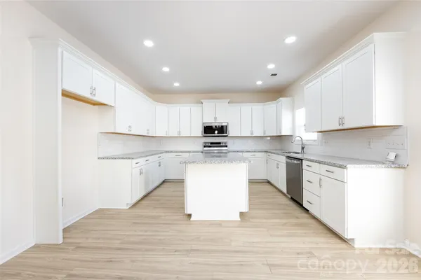 a large kitchen with kitchen island a sink a stove a center island and a window