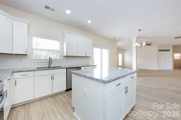 a kitchen with granite countertop white cabinets and stainless steel appliances
