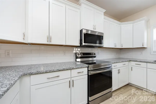 a kitchen with granite countertop white cabinets and black appliances