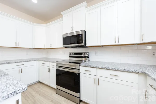 a kitchen with granite countertop white cabinets and stainless steel appliances