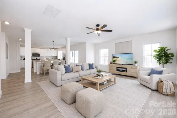 a living room with furniture a flat screen tv and kitchen view