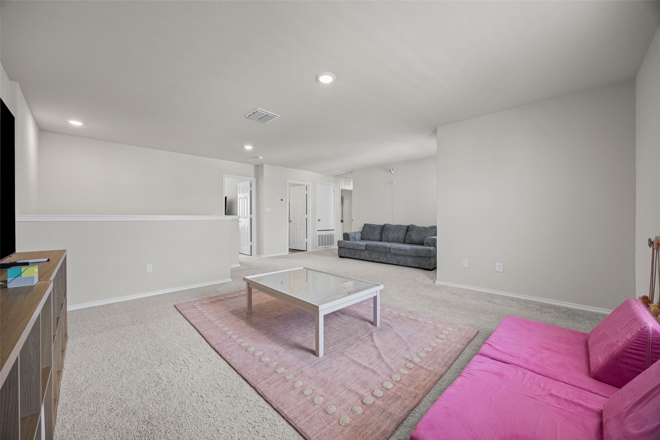 208 Orange Road Buda, TX 78610 - Photo 17 of 31 A spacious recreation room, bathed in neutral tones, offers ample space for relaxation and activities.