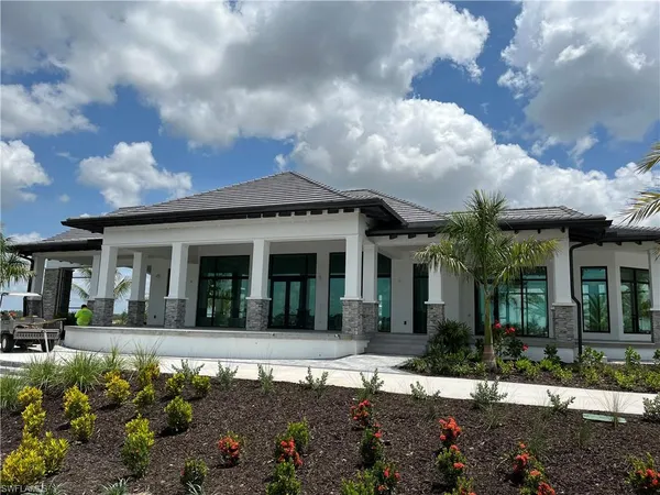 a front view of a house with a garden and lake view