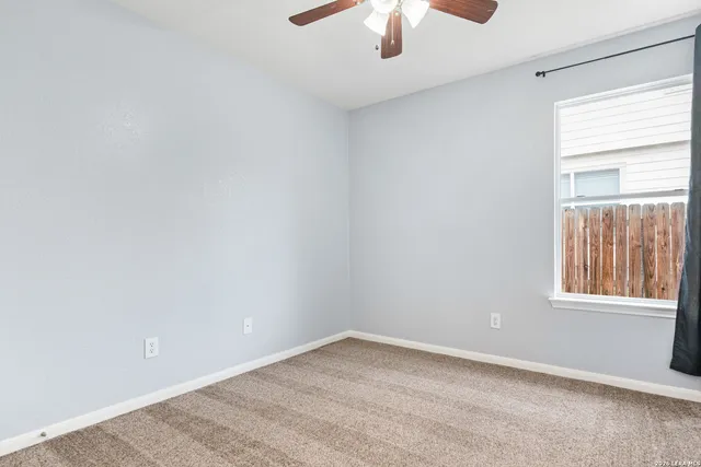 an empty room with a window and a ceiling fan