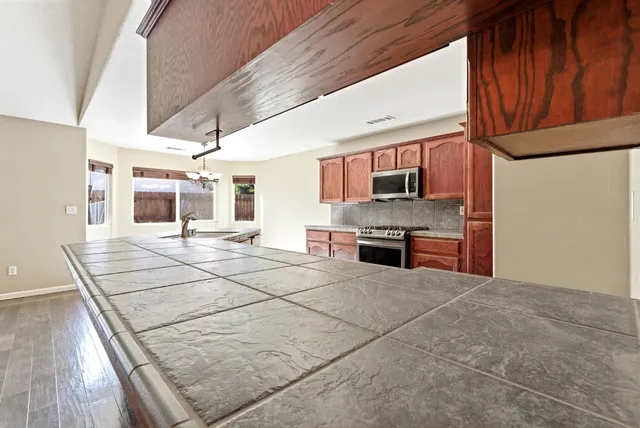 a open kitchen with stainless steel appliances kitchen island granite countertop a stove and a sink with granite countertops