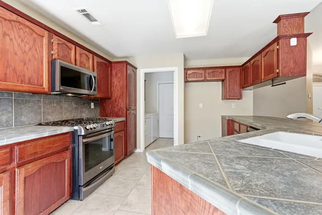 a kitchen with stainless steel appliances granite countertop a stove microwave and cabinets