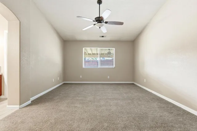 an empty room with a window and a ceiling fan