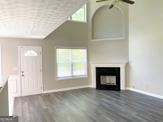 646 Lakes Circle Lithonia, GA 30058 - Photo 11 of 32 an empty room with wooden floor a fireplace and windows