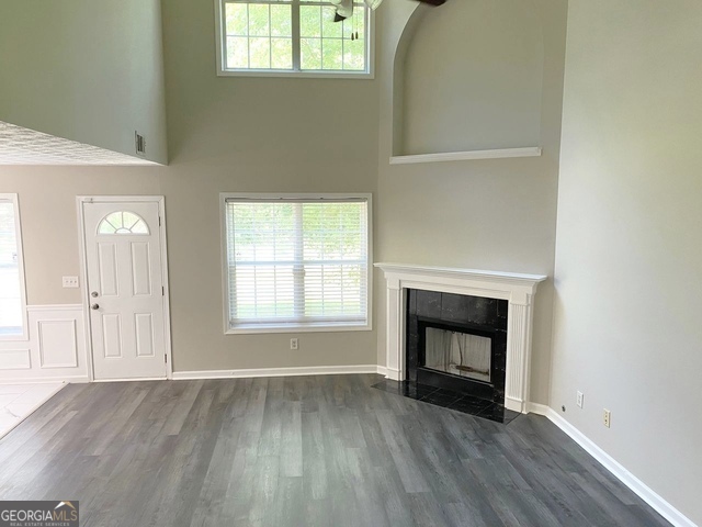 646 Lakes Circle Lithonia, GA 30058 - Photo 13 of 32 an empty room with wooden floor fireplace and windows