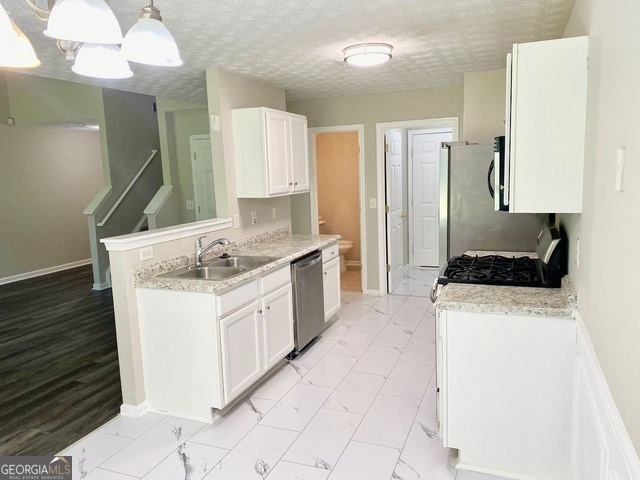 646 Lakes Circle Lithonia, GA 30058 - Photo 5 of 32 a kitchen with granite countertop a sink a stove and a refrigerator